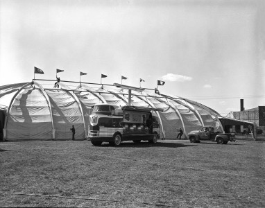 PRODUCT EXPERT NOTE: 1953 aerial view of P.O.P. being set up; with 1940 Futurliner "Diesel Power" open for displayENVELOPE INFO:  4-27-53; Parade of Progress; 4x5, 8x10ORIGINAL CLIENT: GM Pub. Rel.SIGN: "Diesel Power Parade"RESEARCH NOTE: The brainchild of Charles Kettering, the Parade of Progress brought Worlds Fair type non-commercial entertaining, educational exhibitions to rural and small towns across the USA using custom-built Streamliners (1935-1940) and Futurliners (1940s and 1950s). [SOURCE: GM Text File]INDEXER NOTE: Location is Lexington, Kentucky according to Parade of Progress schedule